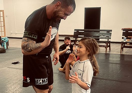 Jiu Jitsu Coach high fiving a kid